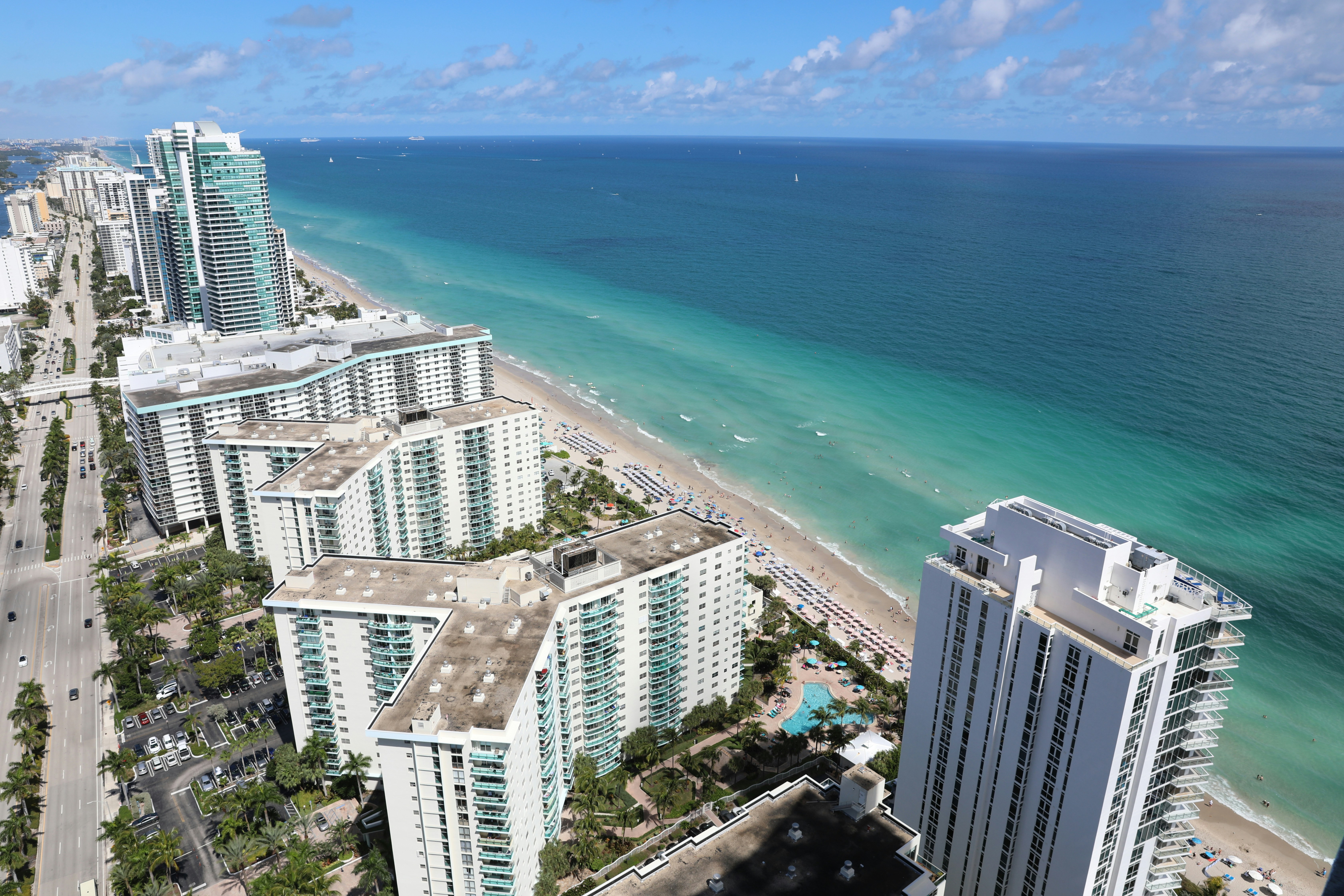 Aerial view of Hallandale Beach oceanfront condominiums, sandy beach, turquoise Atlantic Ocean, and luxury coastal skyline in Hallandale Beach, Florida.