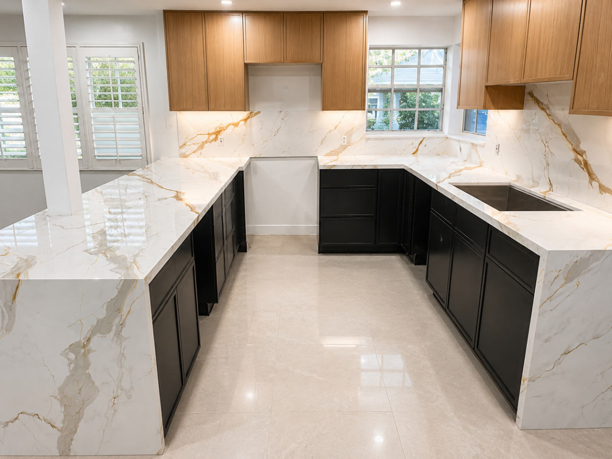 U-shaped kitchen remodel with Calacatta Gold quartz countertops, dramatic waterfall island panels, full-height quartz backsplash, black custom cabinetry, and natural wood upper cabinets by King of Quartz in South Florida.